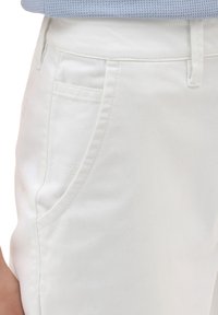 Witte katoenen broek met een gladde textuur, vijf zakken, en een rechte snit. De tailleband heeft riemlussen en een subtiele gestikte detail.