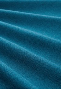 Türkisfarbener Stoff mit glatter Textur, sichtbarem Strickmuster und sanften Falten, die ein drapiertes Erscheinungsbild erzeugen. Gleichmäßige Farbabgabe im gesamten Stoff.