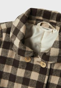 Cappotto di lana a scacchi marrone e beige con fodera beige, colletto alto, due bottoni in legno e etichetta "Lil’ Atelier" all'interno.