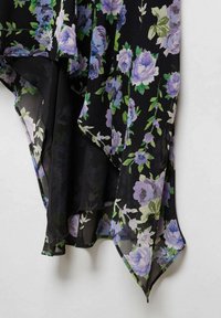 Tissu noir transparent avec un motif floral de roses violettes et de feuilles vertes, présentant un ourlet fluide et incliné ainsi qu'une texture douce.