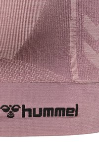 Rosa träningskläder i tyg med texturerad ribb och ett geometriskt mönster. Svart "hummel"-logotyp längs nederkanten. Mjuk, figurnära design.