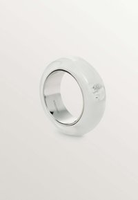 Anillo de resina blanca translúcida con una superficie lisa y un interior en tono plateado, con un detalle acentuado claro en un lado.