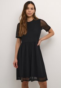 Crna haljina s prilagođenim korzetom i lepršavom suknjom. Providne kratke rukave i okrugli izrez. Lagana tkanina s glatkom teksturom.