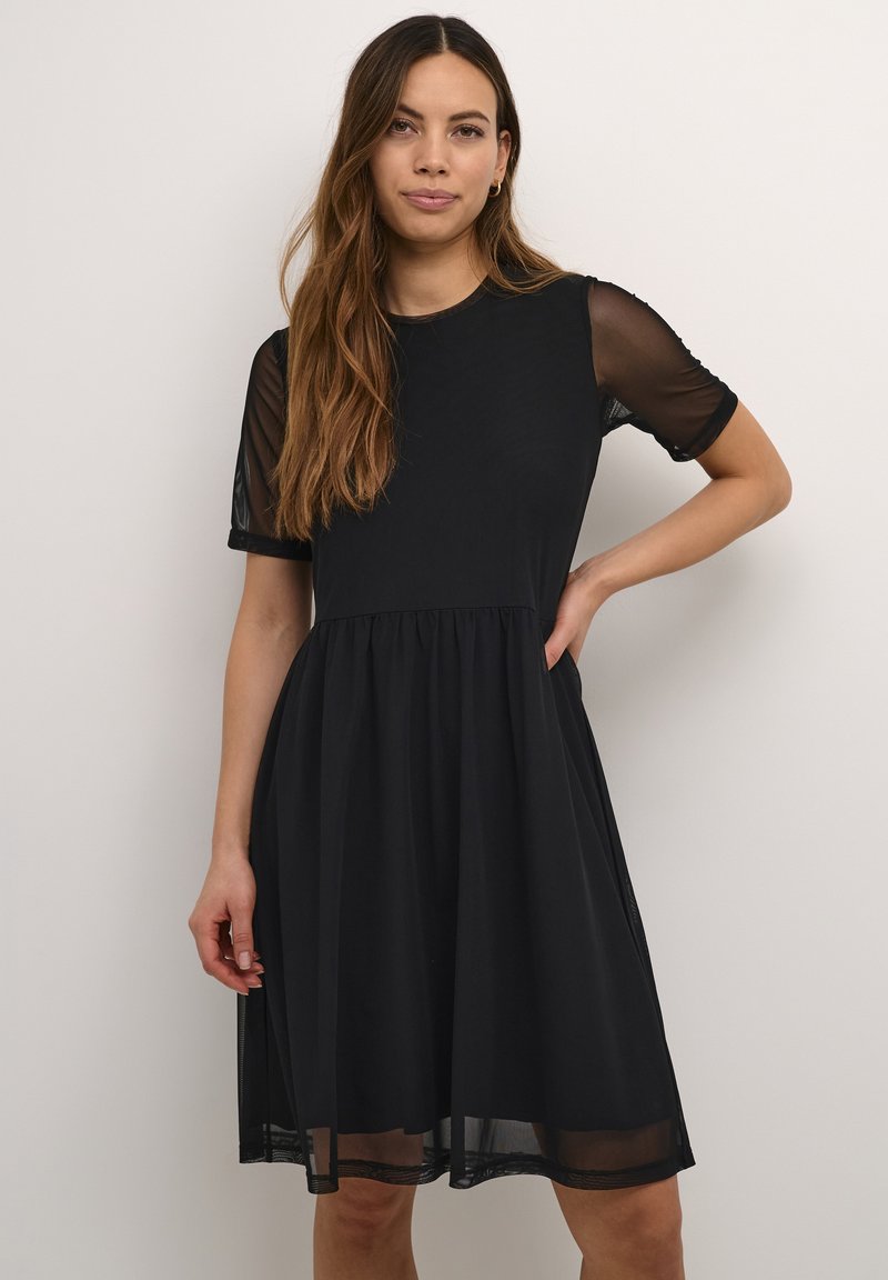 Crna haljina s prilagođenim korzetom i lepršavom suknjom. Providne kratke rukave i okrugli izrez. Lagana tkanina s glatkom teksturom.