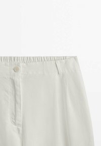 Pantalon blanc avec taille élastique, fermeture par bouton et passants de ceinture, présenté de la taille à mi-cuisse sur un fond uni.