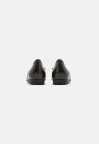 Zwarte leren schoenen met een gladde textuur, ronde neus, lage hak en minimalistisch ontwerp. Heeft een subtiele naad langs de zijkanten.