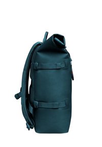 Teal roll-top reppu, joka on valmistettu vedenpitävästä materiaalista, säädettävillä hihnoilla ja pehmustetulla selkäosalla. Mukana sivulukot turvalliseen sulkemiseen.