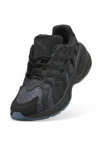 Černé atletické boty s texturovaným svrškem, unikátním síťkovým překrytím a modrou gumovou podrážkou. Mají šněrovací design a logo Puma.