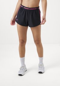 Juodi sportiniai šortai su rožiniais akcentais ir "Under Armour" logotipu ant juosmens; avimi su baltais sportbačiais ir kojinėmis.
