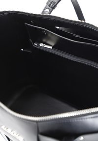 Musta nahkalaukku, jonka sisällä on sileä pinta, useita taskuja ja vetoketjullinen lokero. Vetoketju sulkeutuu ylhäältä.