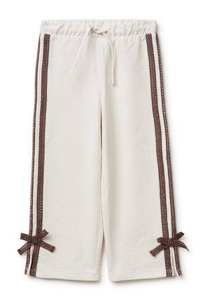 Pantalon à jambes larges couleur crème avec bandes latérales en dentelle marron et nœuds assortis près de l'ourlet, avec une taille à cordon.