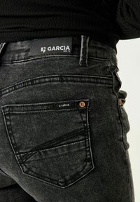 Czarne dżinsy denimowe o dopasowanym kroju, z klasyczną tylną kieszenią i metką oznaczoną "GARCIA EST. 72" w pasie. Teksturowany materiał.