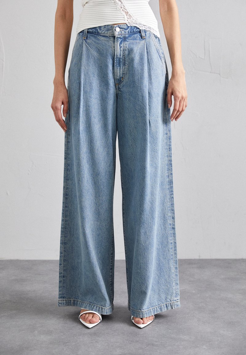 Wide-leg jeans in light blue denim with a pleated front, high waist, button closure, and side pockets. Smooth texture with slight fading.