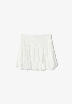 White, textured mini skirt with a layered, ruffled hem. Made of lightweight fabric, featuring a crinkled appearance and elastic waistband.