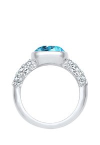 Ringen har en stor, facetteret blå ædelsten, omkranset af mindre klare sten, der er indsat i en poleret sølvring. Der er teksturerede detaljer på siderne.