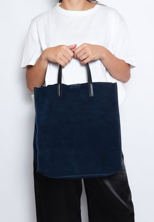 Borsa a spalla in suede blu navy con manici in pelle nera. Forma rettangolare, design minimalista, superficie liscia e senza motivi o dettagli visibili.
