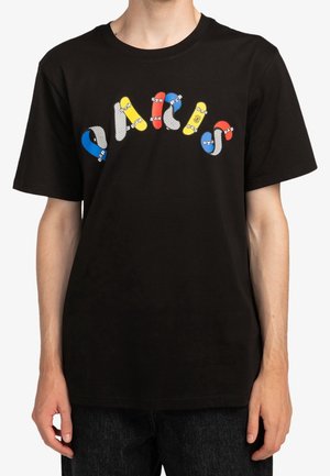 Personne portant un t-shirt noir avec des motifs incurvés et colorés de skateboard disposés sur la poitrine.