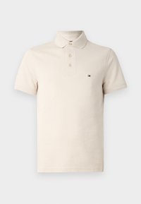 Polo beige en coton, avec un col classique, trois boutons, des manches courtes et un petit logo sur la poitrine.