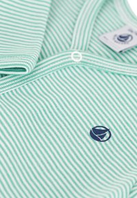 Polo a righe verdi e bianche realizzato in tessuto morbido, dotato di colletto, chiusura con bottoni e un piccolo logo blu navy sul petto.