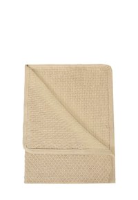 Beżowy, teksturowany koc z wzorem tkanym, z gładką ramką. Jeden róg złożony, aby pokazać kontrastującą teksturę pod spodem.