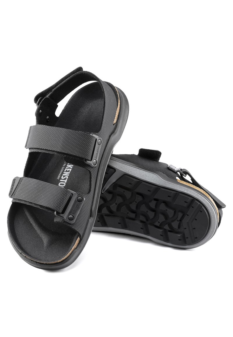 Sandales noires avec un design de sangle texturé, deux sangles velcro ajustables, une semelle en caoutchouc et un semelle intérieure en liège pour le confort.