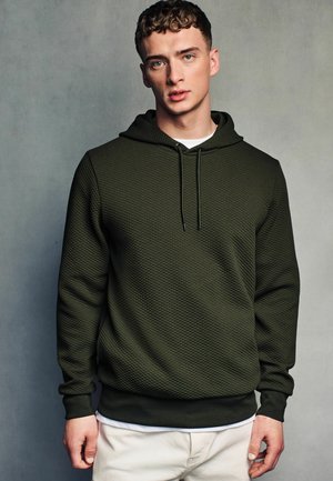 Green patterned hoodie with a textured surface, featuring a drawstring hood and ribbed cuffs, layered over a white T-shirt.