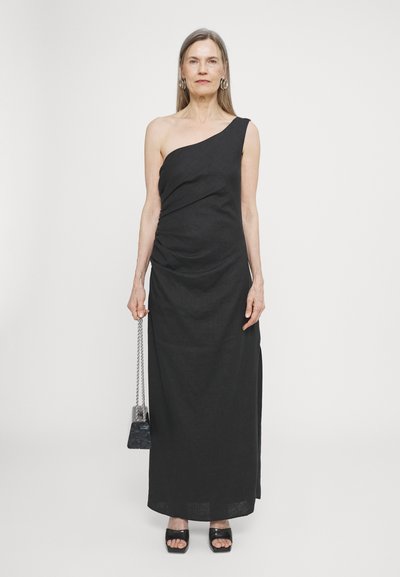 Black, one-shoulder maxi dress with draped detailing, made of lightweight fabric. Paired with a small black bag and black platform sandals.