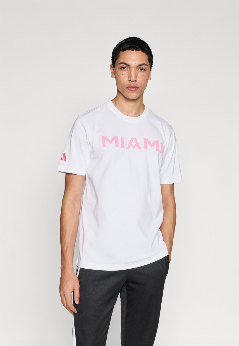 Λευκό βαμβακερό t-shirt με την επιγραφή "MIAMI" σε έντονα ροζ γράμματα στο στήθος. Διαθέτει κοντά μανίκια και στρογγυλή λαιμόκοψη.