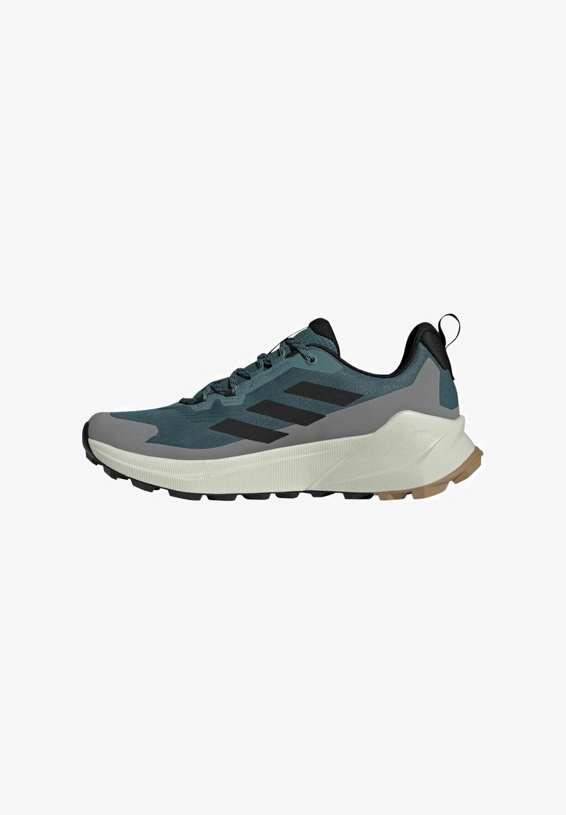 Trailrunning schoen in teal en grijs. Voorzien van zwarte accenten, een gestructureerde bovenkant en een robuuste loopzool met gripnoppen voor betere grip.