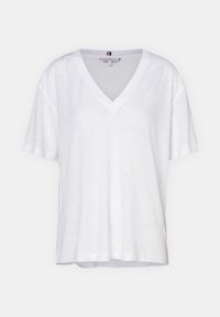 Hvid kortærmet T-shirt med V-hals, lavet af et letvægtsstof, har en afslappet pasform og subtil tekstur. Ingen synlige mønstre eller accenter.