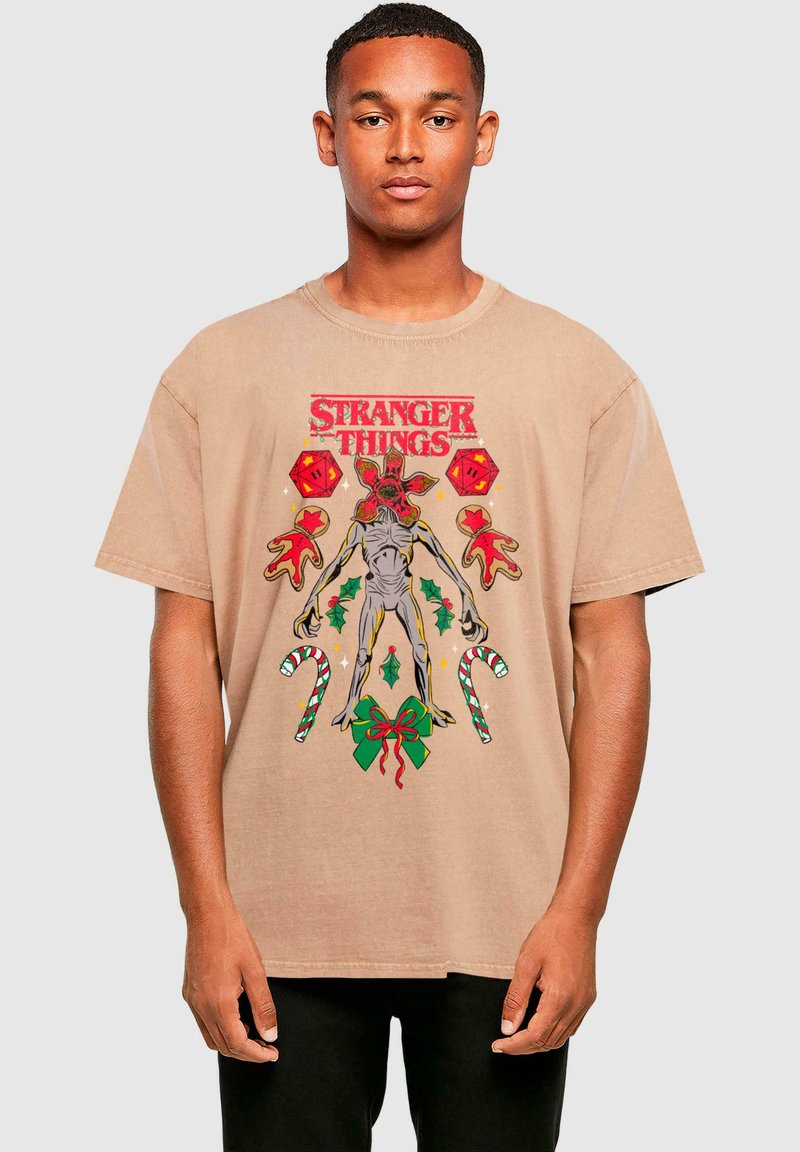 Béžové bavlněné tričko s pestrou grafikou tvora, cukrovinek a vánočních prvků, s textem "Stranger Things".