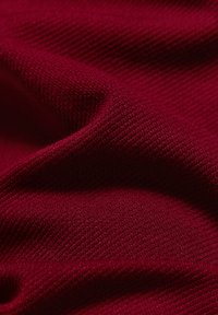 Strukturierter, gerippter Stoff in tiefrot, der feine, gleichmäßige Fasern und ein weiches, leicht dehnbares Aussehen zeigt.