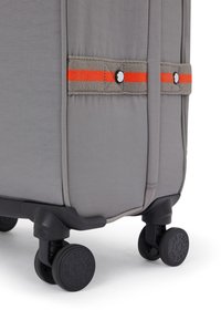 Gray suitcase with orange and gray accents, featuring four black wheels and a textured, fabric surface with visible stitching details.