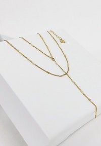 Złota naszyjnik warstwowy z delikatnymi ogniwami i projektem lariatu, z zapięciem i regulowaną długością. Prezentowany na białym tle.
