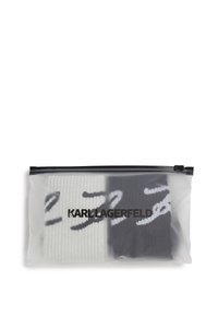 Dos pares de calcetines en una bolsa de plástico transparente. Un par es blanco con rayas negras, y el otro es negro con rayas blancas.