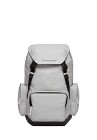 Sac à dos en tissu gris avec un rabat supérieur, des bretelles noires réglables, une poche avant et des compartiments latéraux arrondis. Présente un accent noir en bas.