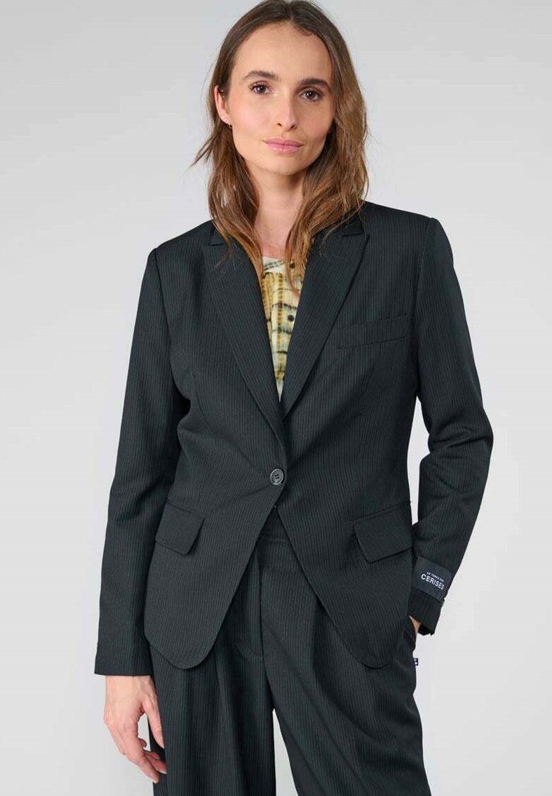 Zwarte pinstripe blazer met een enkele knoop, twee voorzakken en een getailleerde pasvorm. Draag het over een gepatterde top, met een soepele stofstructuur.