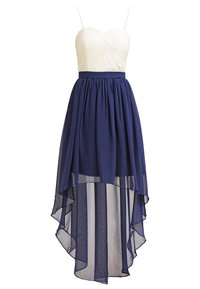 Sukienka z dopasowanym kremowym gorsetem z plisowaniami i granatową spódnicą w stylu high-low wykonaną z przezroczystego materiału, tworzącą efekt warstwowy.
