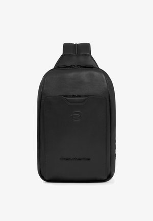 Zwarte leren schouderrugzak met ritsvak aan de voorkant, geperst logo en verstelbare gewatteerde band zichtbaar aan de bovenkant.
