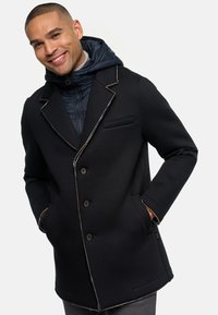 Black coat with a textured finish, tailored fit, three buttons, contrasting stitch accents, and a removable blue hooded inner layer.