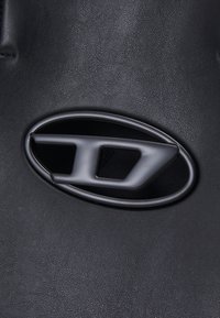 Surface en cuir noir texturé avec une poignée métallique élégante de forme ovale, présentant un motif géométrique découpé.