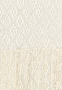 Bílá texturovaná látka s hexagonálním krajkovým vzorem nahoře, přecházející do vlnitého, volně tkaného designu dole.