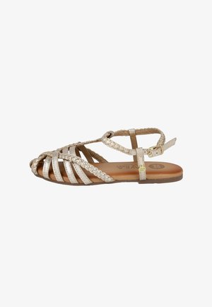 Sandalia plana metálica dorada con tiras trenzadas y lisas, hebilla en el tobillo y suela acolchada marrón.