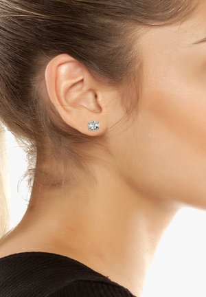 Orecchini a stud in argento con pietre in zirconia cubica trasparenti, caratterizzati da un design squadrato. Texture metallica liscia, posizionata su uno sfondo neutro.