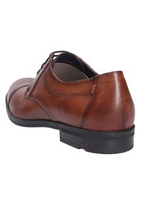 Scarpa in pelle marrone con texture liscia, punta arrotondata e suola in gomma nera. Cuciture dettagliate e un piccolo accento rosso vicino al tallone.