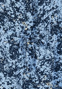 Blå mönstrad tyg som har en blandning av ljus och mörk blått med gula accenter. Inkluderar en framficka och en knuten midja.