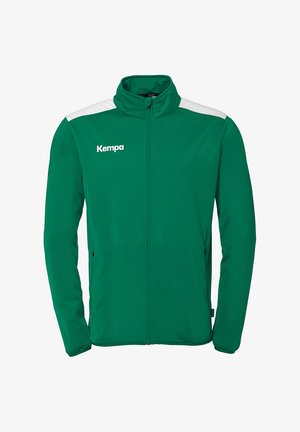 Groene zip-up jack met witte schouderaccenten, met een hoge kraag en zijzakken. Het materiaal lijkt glad en lichtgewicht. "Kempa" logo op de voorkant.