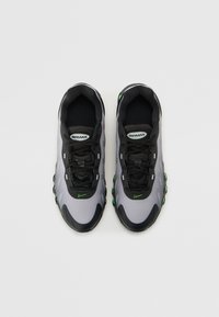 Les baskets Nike Air Max présentent un dessus en maille gris, des accents noirs, des détails verts, une pointe arrondie et un amorti air visible sur la semelle.