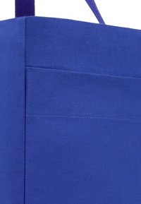 Borsa a spalla in tessuto blu con una forma strutturata, caratterizzata da una consistenza liscia e manici robusti. Tasca laterale visibile su un pannello.
