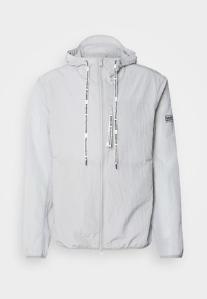 Lichte grijze hoodie-jack gemaakt van een gestructureerde stof. Bevat een rits aan de voorkant, trekkoorden met merktekst en een patch op de mouw.